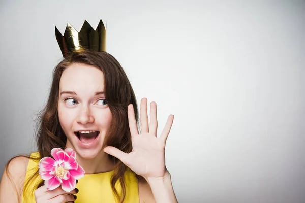 幸せな驚き世界女性の日を祝う彼女の頭に金の冠、手にピンクの花を持った若い女性 — ストック写真