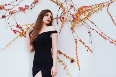 lüks çekici genç bir kadın siyah giysili bir dinlenme zevk duvar tarafından duruyor