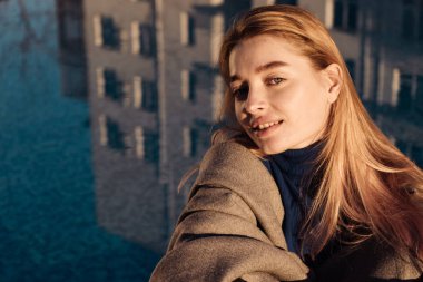 Güneş, mavi havuzun yanında oturan güzel genç sarışın kız gülümseyerek