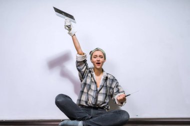 mutlu genç kız Oluşturucu yere oturur, bir spatula tutar, dairede tamirat yapar