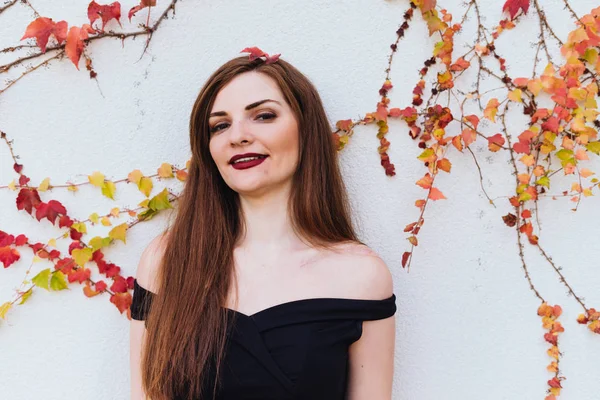 Luxurious beautiful smiling woman in black dress posing against wall, enjoying a rich life — Stock Photo, Image