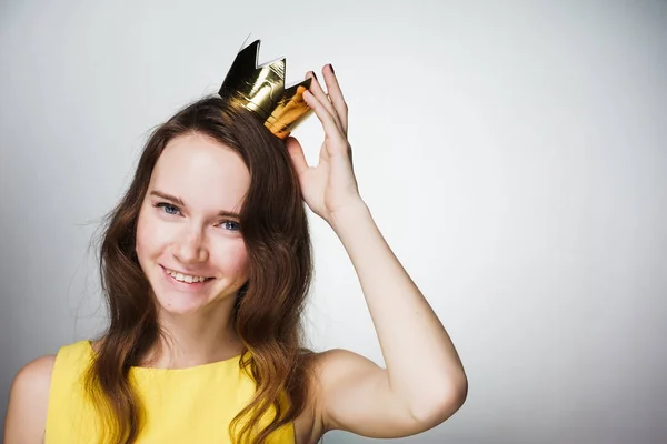 Mooie gelukkig jong meisje in gele jurk, op het hoofd dragen gouden kroon, lacht, het vieren van Moederdag — Stockfoto