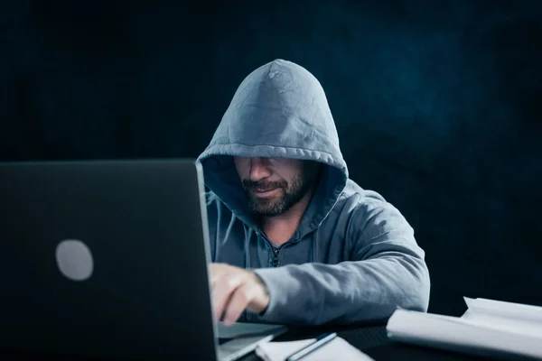 신비로운 교활한 남자 후드 아래 그의 얼굴을 숨기, 어둠 속에서 노트북 해킹 — 스톡 사진