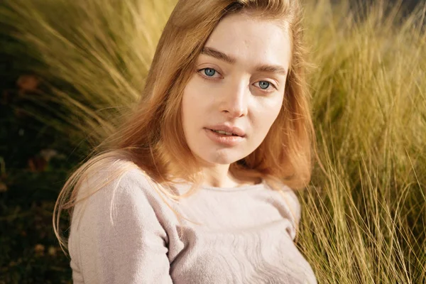 Beautiful woman posing at the camera on a spring field background — Stock Photo, Image