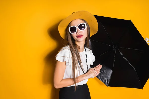 Donna pensierosa in un cappello tiene un ombrello nero in mano — Foto Stock