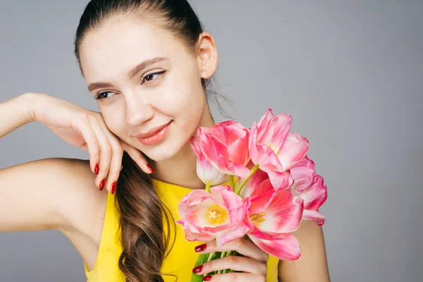 Una mujer pensativa sosteniendo un ramo de tulipanes en sus manos, el 8 de marzo, día de la mujer — Foto de Stock