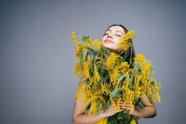 La mujer asombrada que sostiene un ramo de pequeñas flores amarillas, 8 de marzo, Día de la Mujer — Foto de Stock