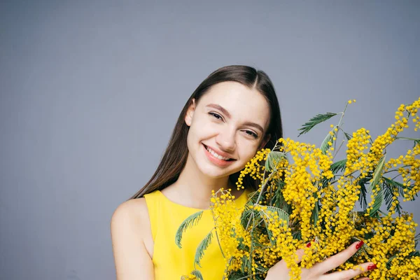 Mujer feliz sosteniendo un ramo de pequeñas flores amarillas, 8 de marzo, día femenino — Foto de Stock