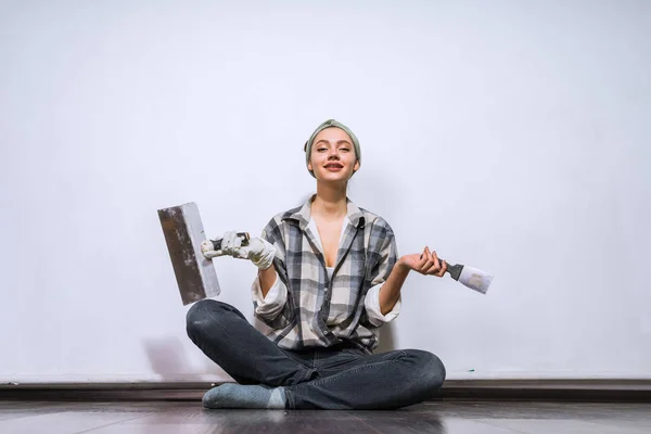 Una mujer cansada sosteniendo un pincel para pintar paredes, reparando un apartamento — Foto de Stock