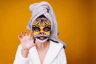 Kaplan maskeli sarı bir arka plan üzerinde bir kadın duruyor