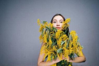 kadın gri bir arka plan üzerinde büyük bir buket çiçek onun elinde tutar.