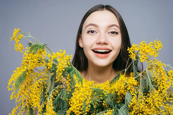 Woman on a gray background holds flowers in her hands — Stock Photo, Image