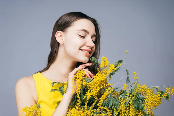 Happy woman holding a bouquet of yellow flowers and looking at them, March 8, mother's day — Stock Photo, Image