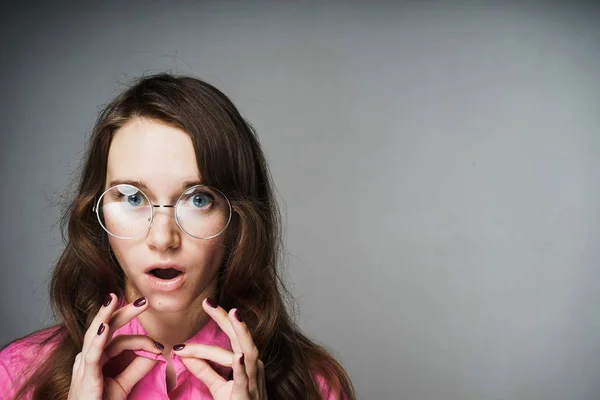 Mulher estudante surpreso com óculos em um fundo cinza — Fotografia de Stock