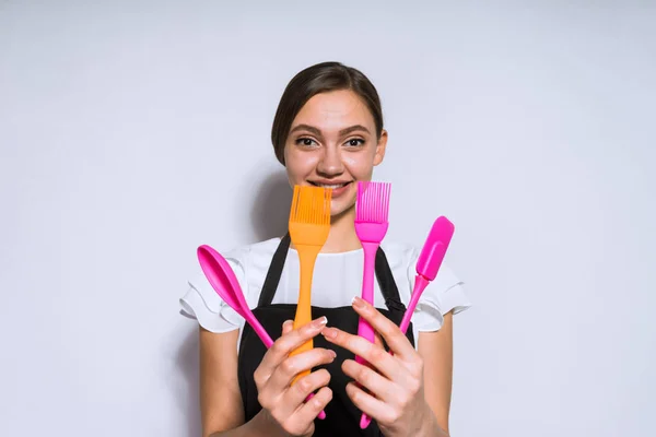 Щаслива жінка тримає кухонну техніку в руках, на сірому фоні — стокове фото