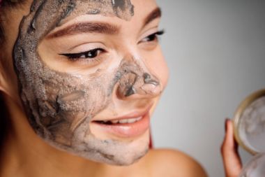 gri bir arka plan üzerinde kadın yüzünde gri bir maske koyar.