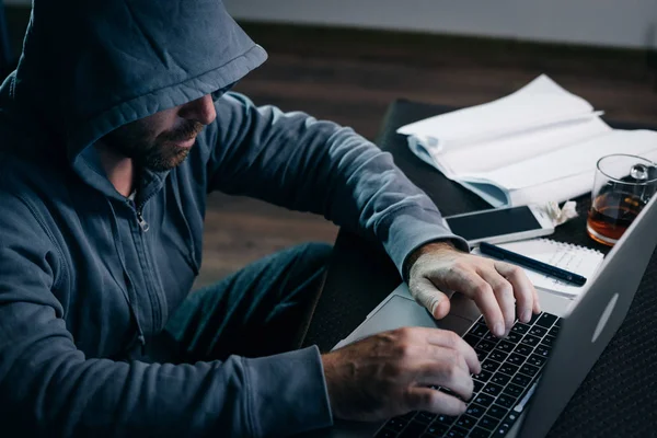 Ein erfahrener Hacker arbeitet zu Hause an einem Laptop — Stockfoto