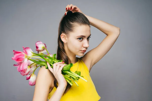 Mujer pensativa sosteniendo un ramo de flores en sus manos, el 8 de marzo — Foto de Stock