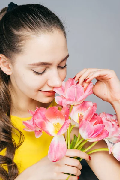 Young beautiful woman holding a bouquet of flowers in her hands, and sniffing them, March 8, women's day — Stock Photo, Image