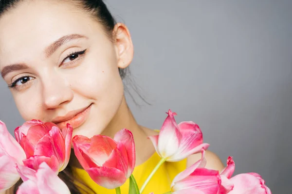 Stupita bella donna che tiene in mano un mazzo di fiori, l '8 marzo, sfondo per un biglietto di auguri — Foto Stock