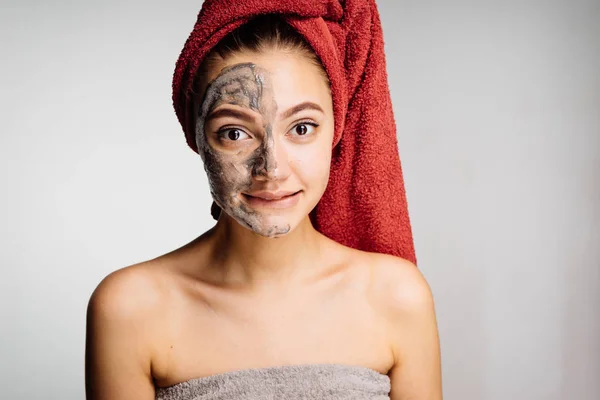 Удивлённая женщина с полотенцем на голове наносит увлажняющую маску — стоковое фото