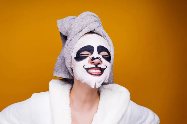 彼女の頭の上のタオルで幸せな女は、顔に保湿マスクを適用します。 — ストック写真