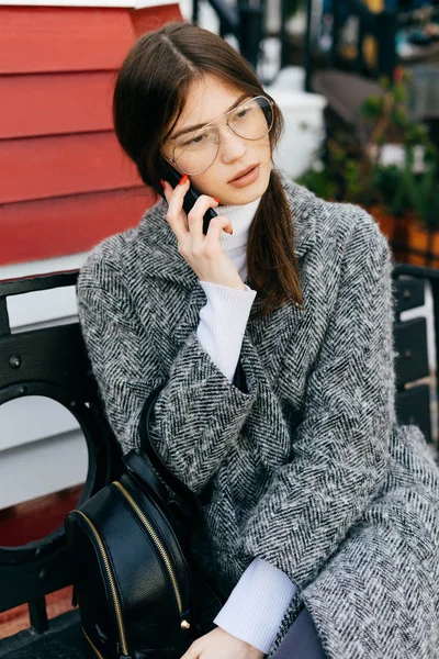 Belle femme assise sur un banc et parlant au téléphone — Photo