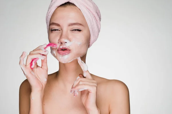 Woman with a towel on her head shaving her face with a razor — Stock Photo, Image