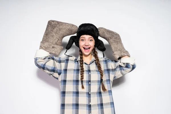 Happy Russian woman in a cap with ear-flaps holds valenki — Stock Photo, Image