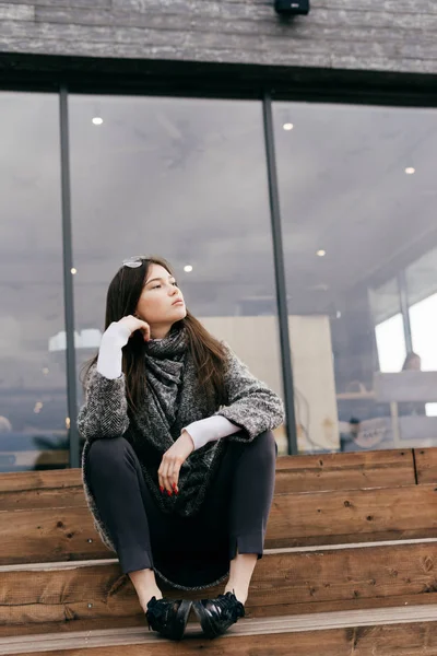 dalgın bir kadın merdivenlerde oturur ve uzak görünüyor