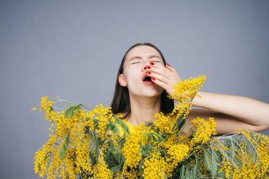 bir buket sarı çiçek tutan ve hapşırma kadın
