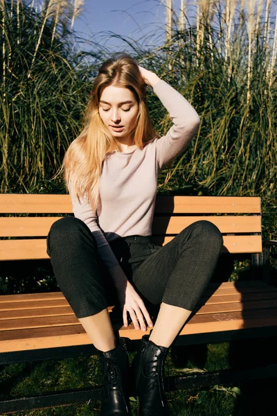 Mulher bonita senta-se em um banco na primavera na rua, resto — Fotografia de Stock