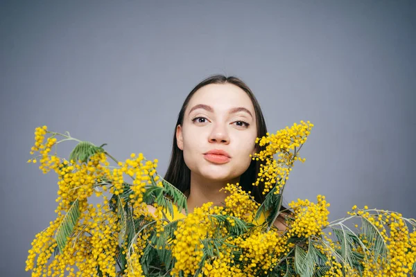 Joven pensativa sosteniendo un ramo de flores amarillas en sus manos — Foto de Stock