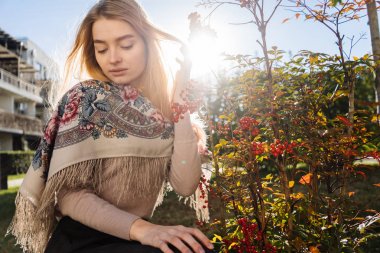 güzel genç kadın kırmızı meyveler bir çalı yanındaki güneşli bir günde oturur.