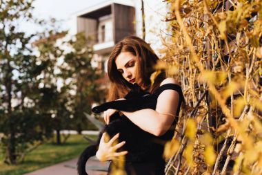 güzel uzun saçlı kız hakkında onu bahçede yürür, siyah bir kedi onun elinde tutan