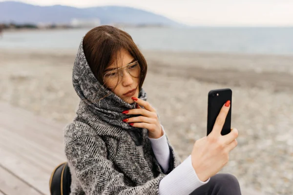 Pensive woman uses a phone for selfie — Stock Photo, Image