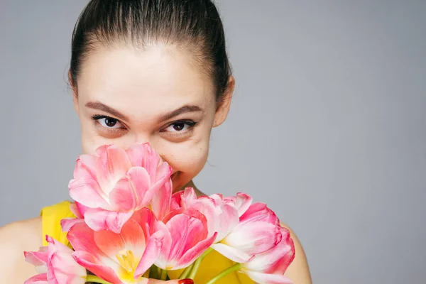 Feliz mujer sobre un fondo de flores, tulipanes, día de la madre, día de la mujer, 8 de marzo — Foto de Stock