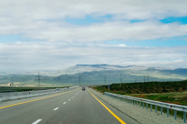 Smooth road, highway, at the foot of mountains and hills, enchanting nature and landscape — Stock Photo, Image