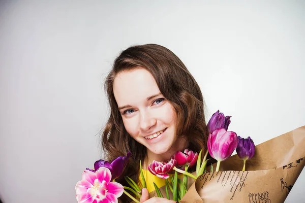 Glad flicka som håller en bukett av doftande blommor, leende, firar en internationella kvinnodagen — Stockfoto