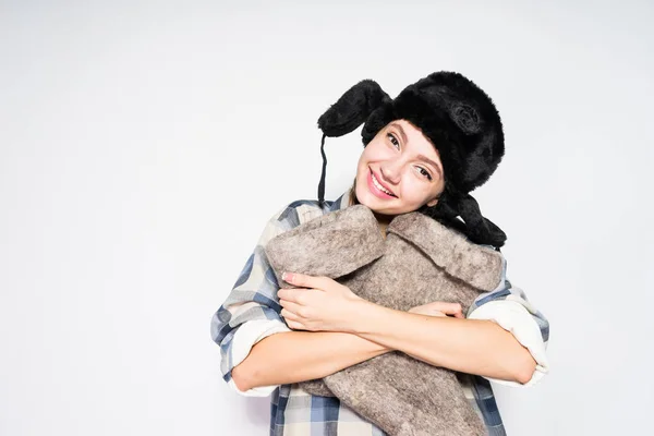 Feliz joven rusa chica en un cálido sombrero de piel sostiene botas de invierno en sus manos — Foto de Stock