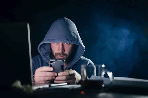 Εγκληματική επικίνδυνος άνθρωπος σε μια κουκούλα αμυχές smartphone — Φωτογραφία Αρχείου