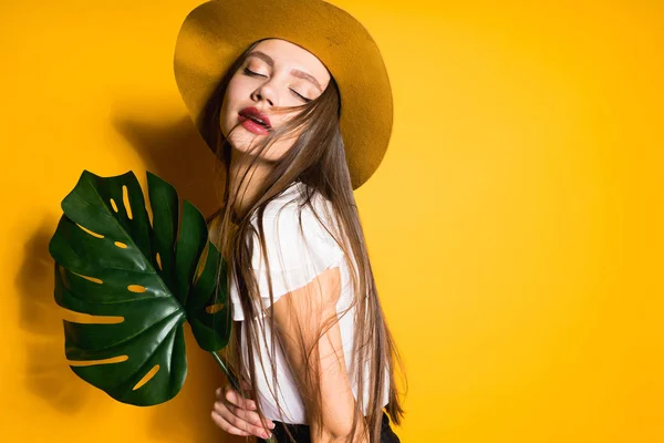 Modello ragazza in grande cappello alla moda tiene una foglia verde — Foto Stock