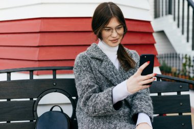Kız bir tezgah açık havada üzerinde oturur ve selfie yapar