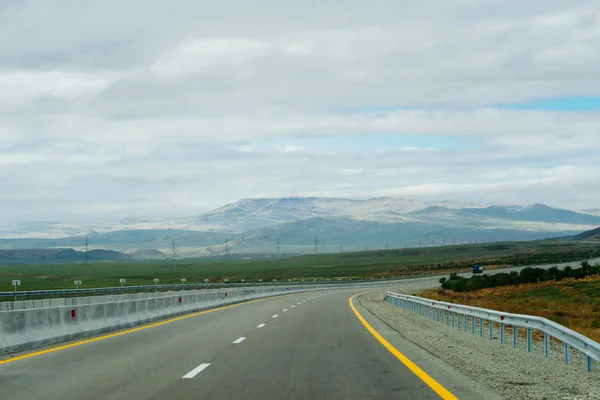 A highway at the foot of mountains and hills, — Stock Photo, Image