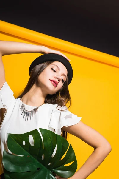 Lány kalapban pózol a sárga háttér — Stock Fotó