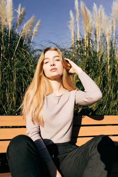 Kız açık havada, güneş ışını bir bankta oturuyor poz — Stok fotoğraf