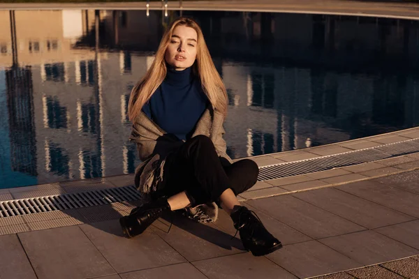 Menina sentada à beira da piscina, desfrutando do sol — Fotografia de Stock