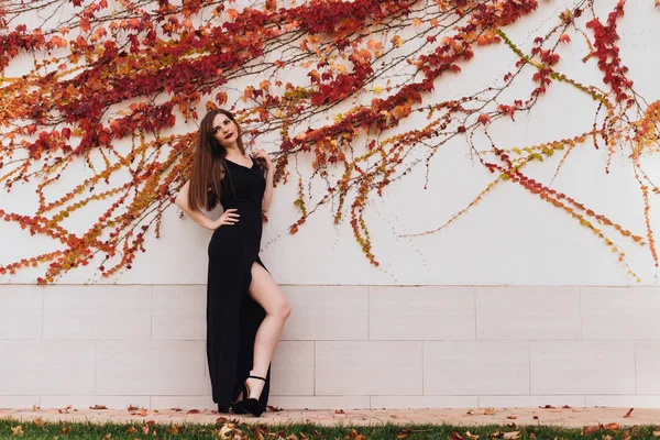 Flicka i svart klänning poserar mot vägg, Utomhus — Stockfoto