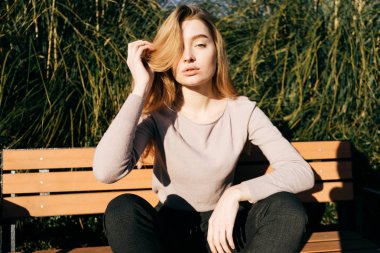 açık havada güneşte bir bankta oturan kız