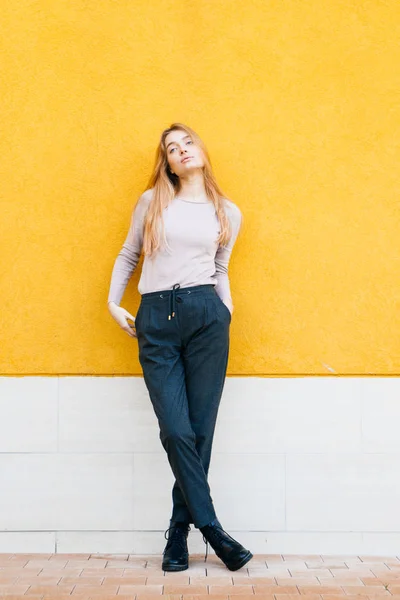 Meisje tegen de achtergrond van een gele muur poseren — Stockfoto